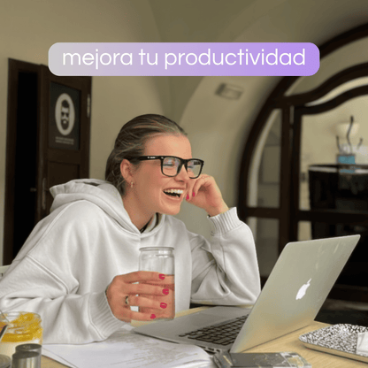 Mujer trabajando con portátil y gafas con filtro de luz azul de Krudo, riendo y mostrando mayor comodidad visual y productividad frente a las pantallas.