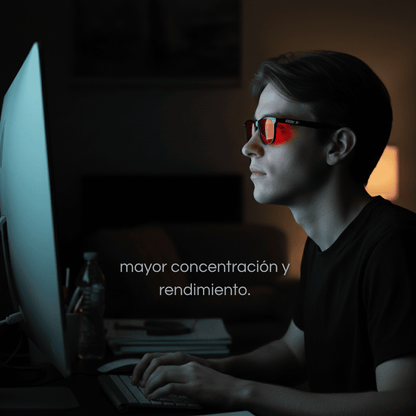 Hombre usando gafas Krudo Night View con filtro rojo bloqueador de luz azul mientras trabaja frente al ordenador, mejorando la concentración y el rendimiento nocturno.